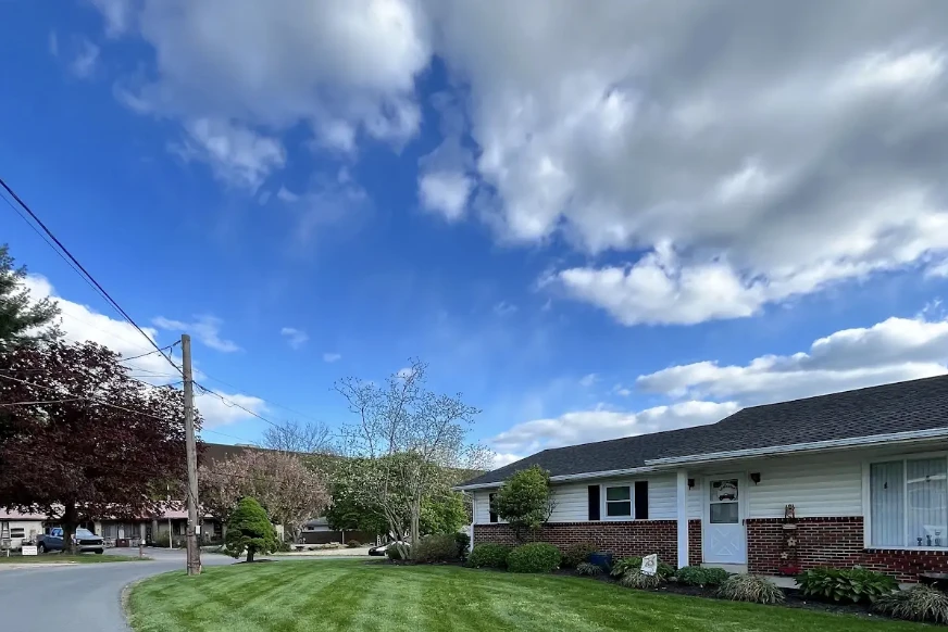 Mowing stripes follow a curved residential lawn beside a mailbox and a one-story brick home.